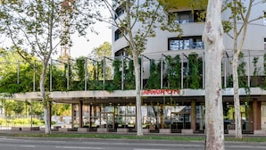 A modern hotel with a glass facade, outdoor seating, and a tree-lined entrance. - Appart'City Confort Mulhouse (Mulhouse)
