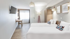 A hotel room with two beds, a desk, a chair, a TV, and a floor lamp. - Appart'City Confort Mulhouse (Mulhouse)