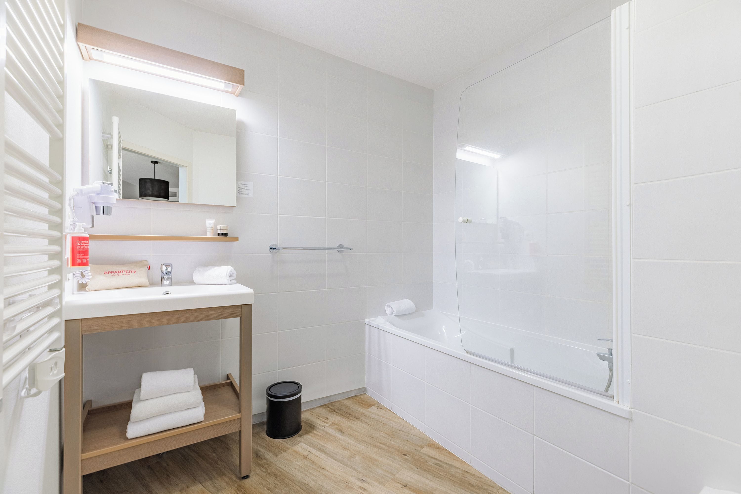 Een moderne badkamer met een witte wastafel, spiegel en douche.