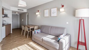 A modern living room with a grey sofa, a dining table, and a red floor lamp. - Appart'City Confort Mulhouse (Mulhouse)