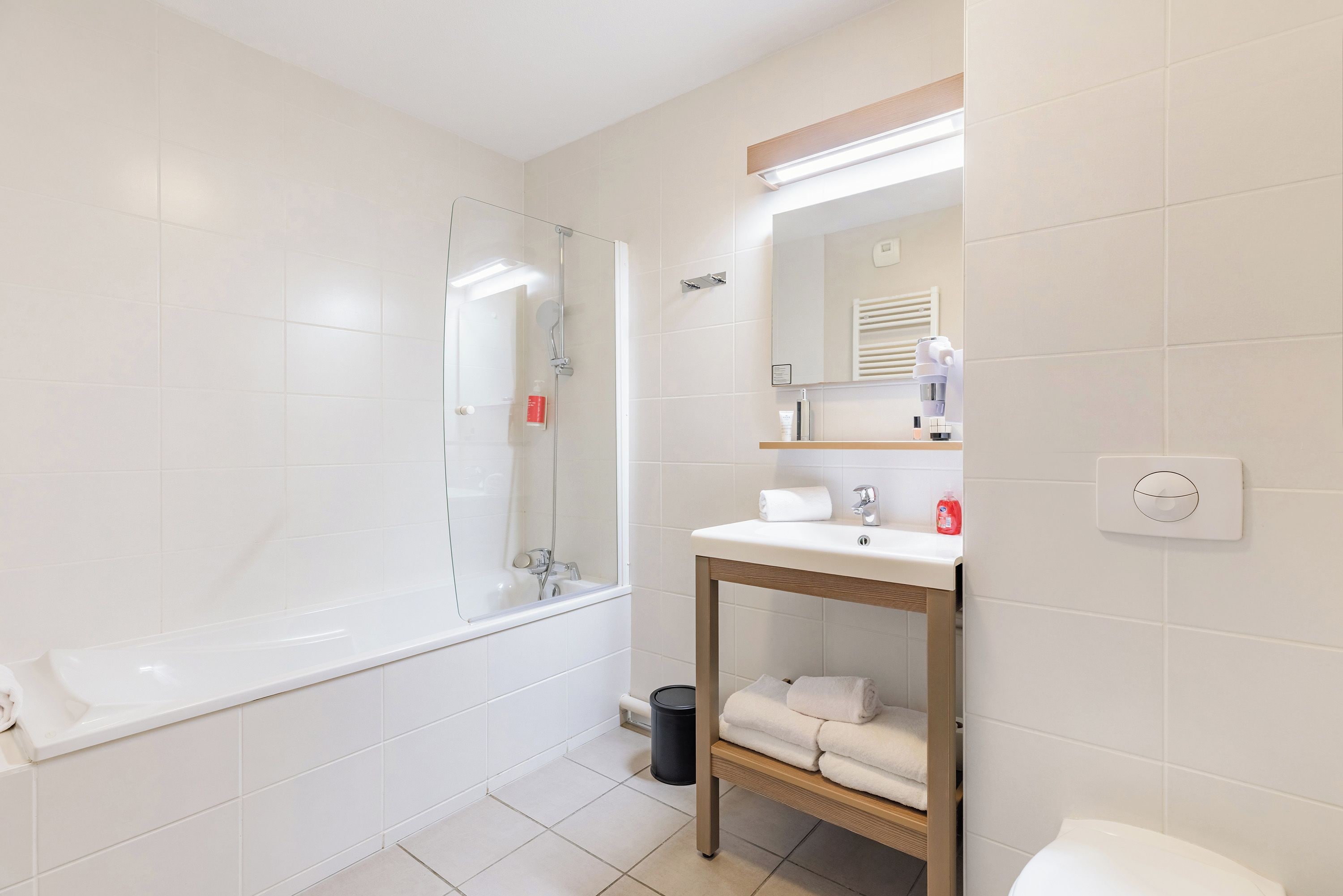 A modern bathroom with a bathtub, a sink with a mirror above it, and a toilet.