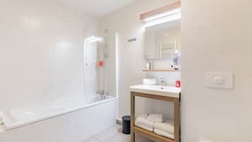 A modern bathroom with a bathtub, a sink with a mirror above it, and a toilet.