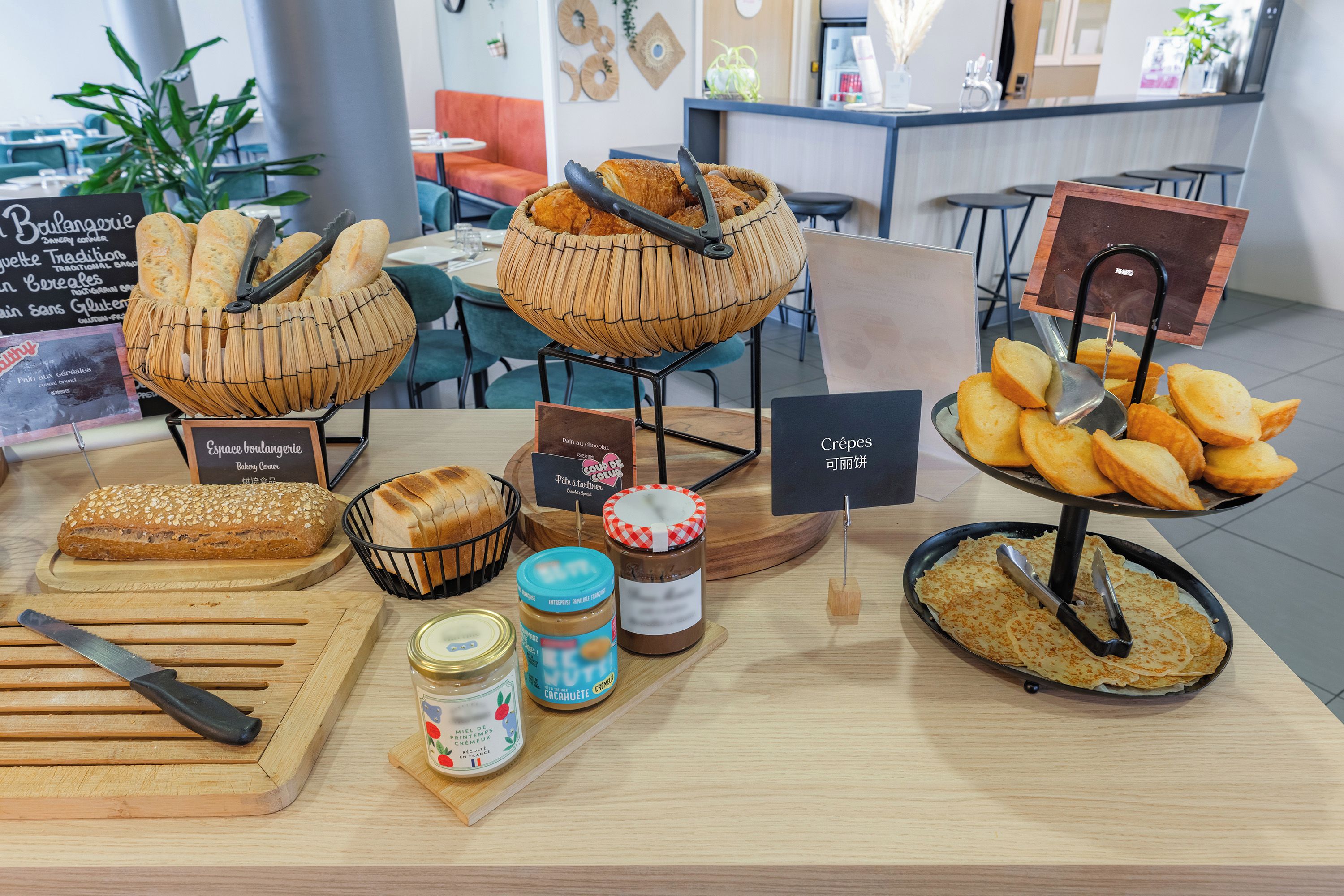 A bakery display with various breads and pastries, a knife, and jars of spreads.