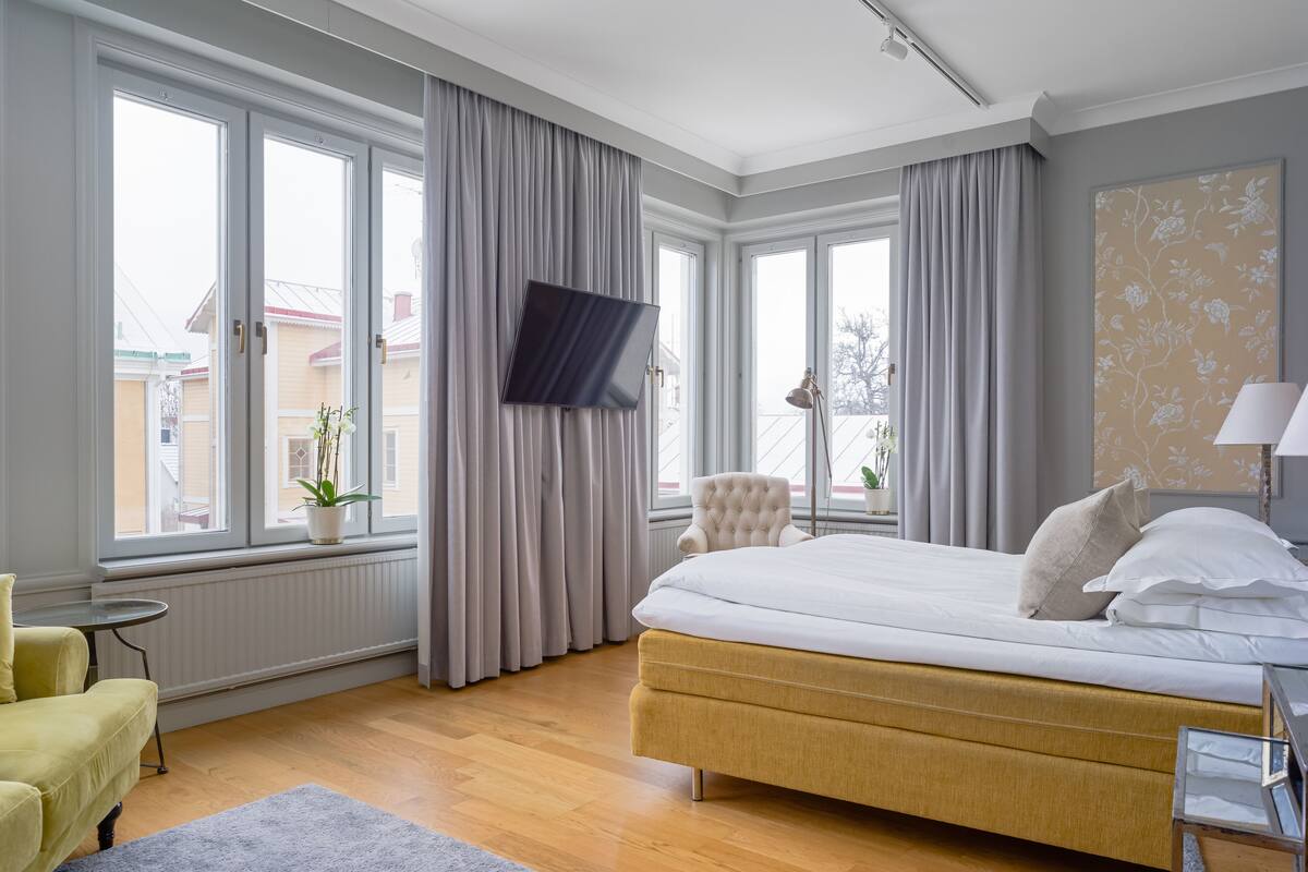 A modern bedroom with a large bed, a television, and a view of the outside.