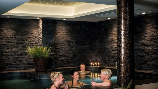 A modern indoor pool area with stone walls and a central column.
