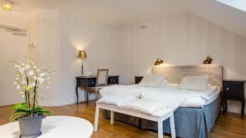 A bedroom with a bed, bedside tables, a desk, a chair, a potted plant, and a small table.