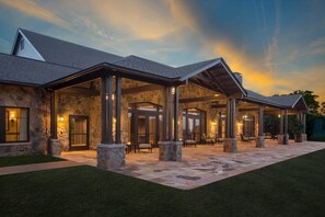 A stone building with a covered patio area, stone pillars, and outdoor seating.
