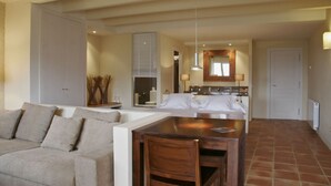 Uma sala de estar moderna com sofá, mesa de jantar de madeira e área de cozinha ao fundo.
