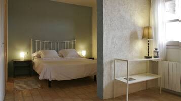 Un dormitorio con cama, mesitas de noche, lámpara, estante y radiador.