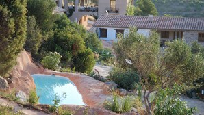 Uma villa com piscina, rodeada por vegetação e colinas.