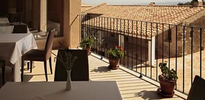 Un balcon avec une table, des chaises et des plantes en pot.