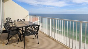 Un balcón con mesa y sillas, con vista a una playa y al océano.