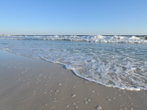 A beach with gentle waves and footprints in the sand. - Lighthouse by Wyndham Vacation Rentals (Gulf Shores)
