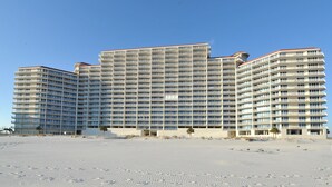 Un hotel grande de varios pisos con un diseño arquitectónico moderno, destacando una fachada simétrica y numerosos balcones.