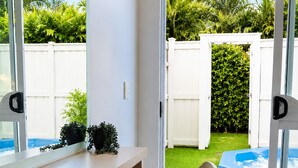 A room with a sliding glass door leading to a backyard with a pool and greenery. - Alpin Motel & Conference Centre (Rotorua)