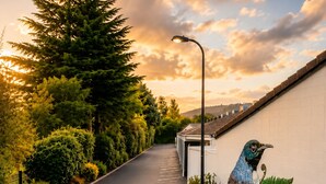 A road lined with trees and a mural of a bird on a building. - Alpin Motel & Conference Centre (Rotorua)