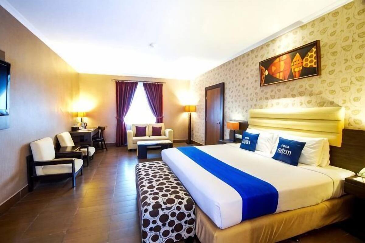 Una habitación de hotel con una cama grande, un escritorio, una silla, un sofá y un banco estampado.