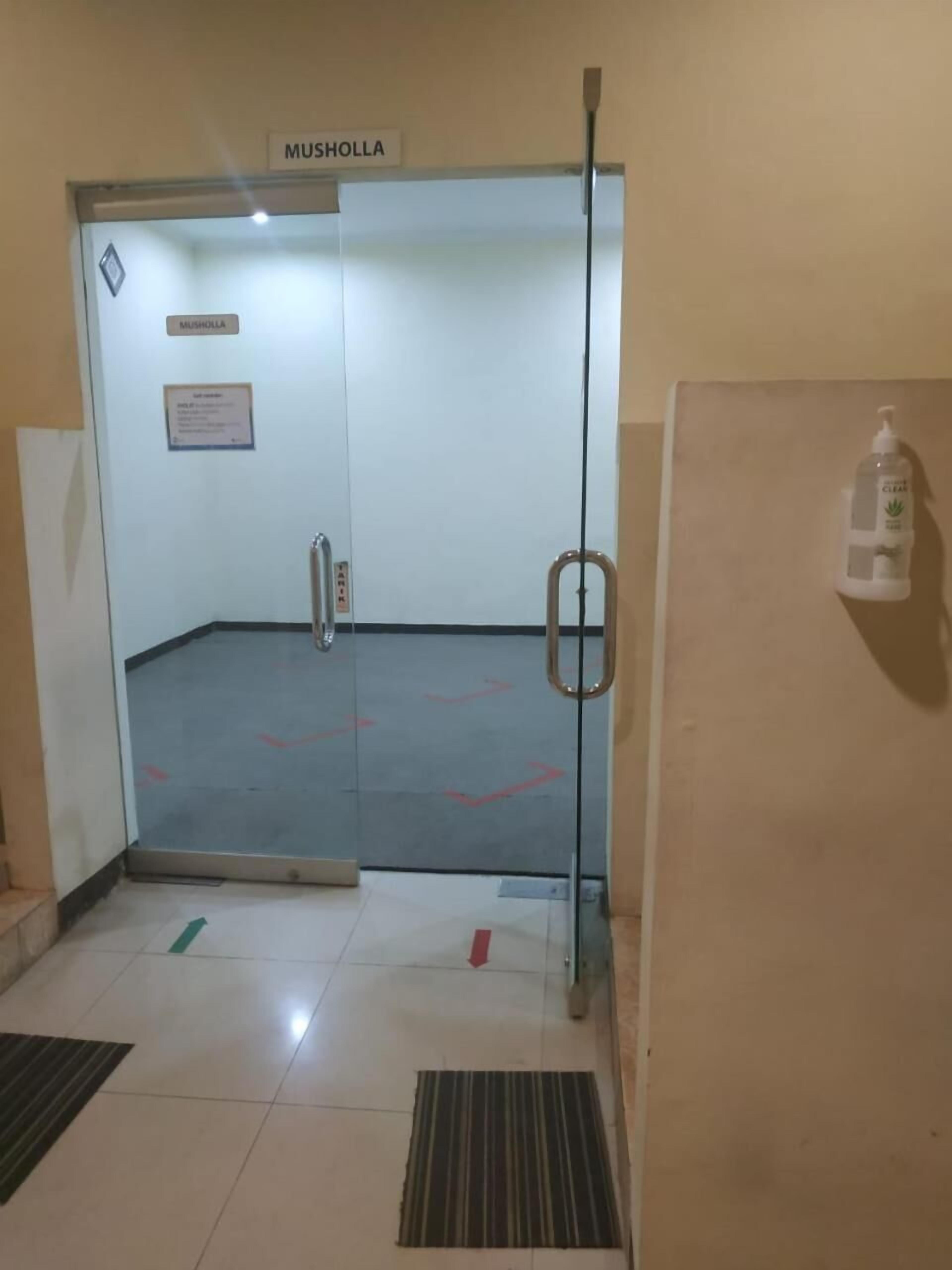 An elevator with a sign reading "MUSHOLLA" and a handrail.