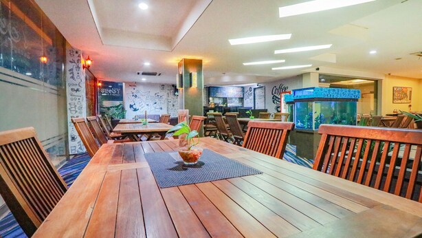 Een restaurant met houten tafels en stoelen, een menubord en een koffieapparaat.