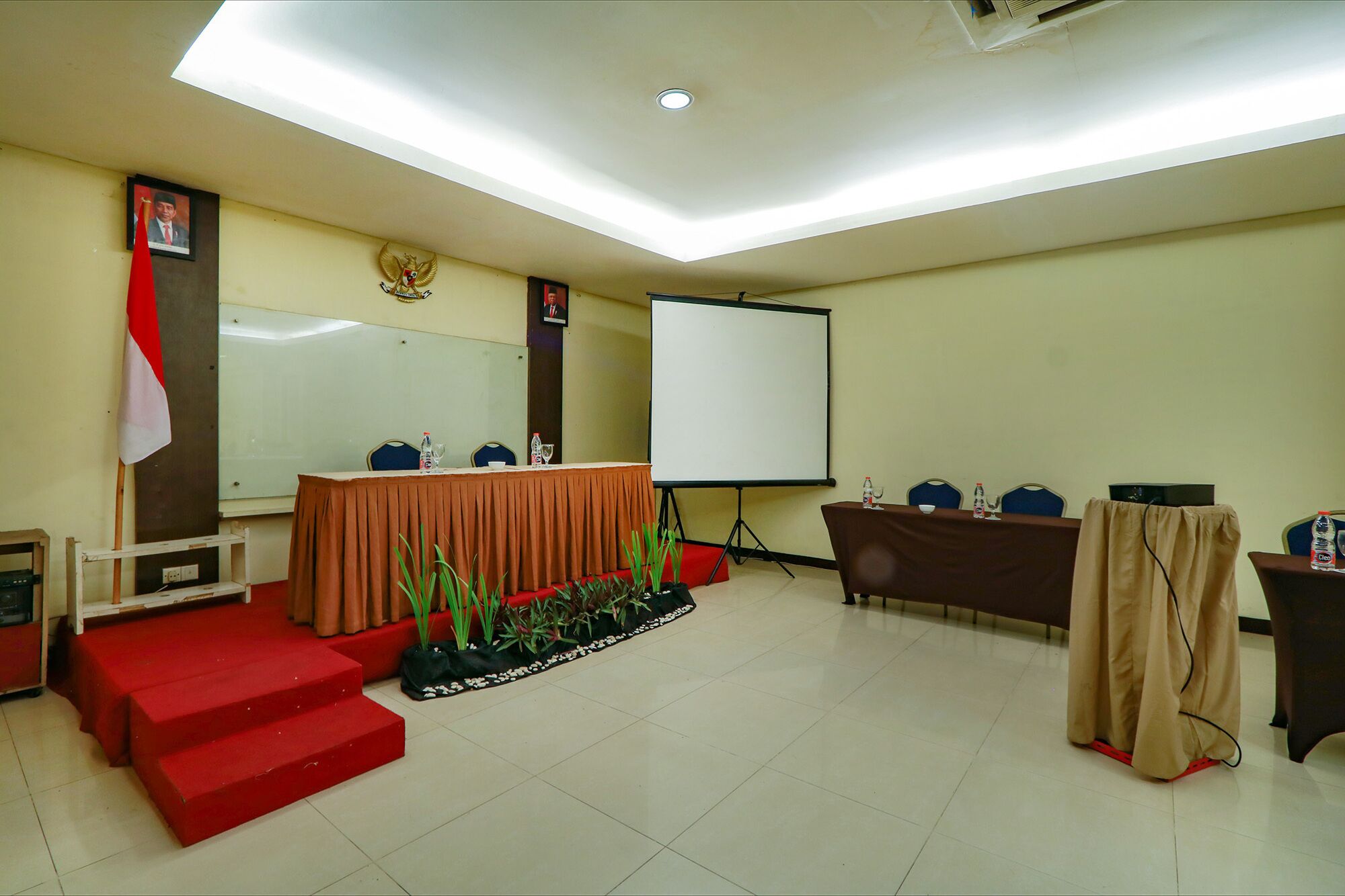 A conference room with a stage, a podium, a whiteboard, and a flag.