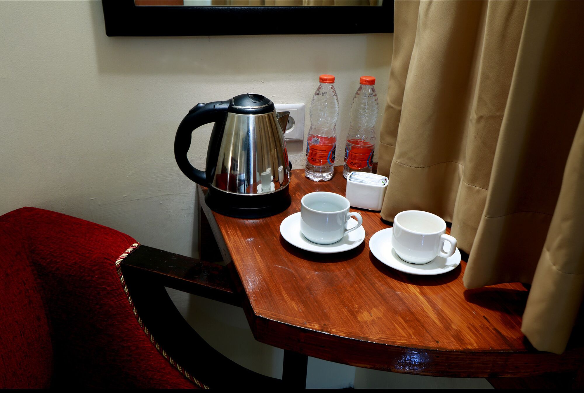 A wooden table with a kettle, two water bottles, and two white cups.