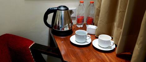 A wooden table with a kettle, two water bottles, and two white cups.