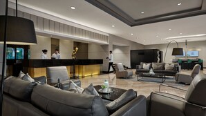 Een moderne lobby met lederen banken, een receptiebalie en een bar.