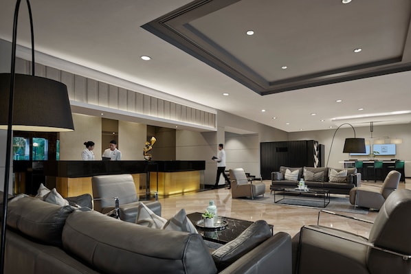 A modern lobby with leather sofas, a reception desk, and a bar area.