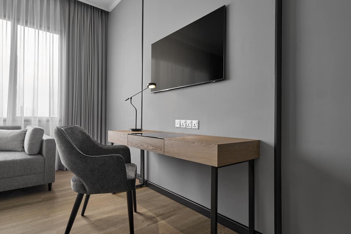 Een moderne kamer met een bureau, stoel en een aan de muur bevestigde televisie.