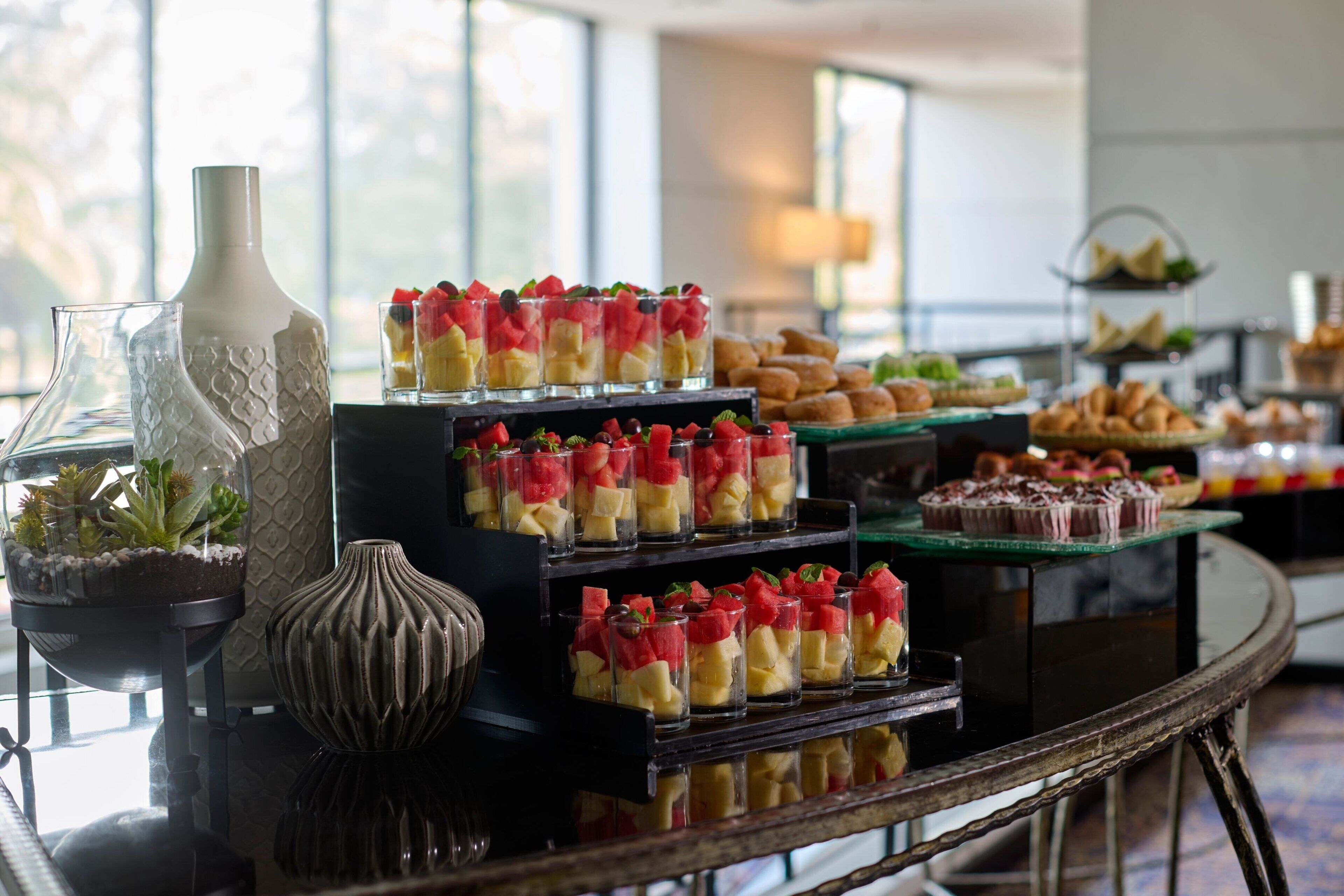 Una mesa de buffet con diversos alimentos y jarrones decorativos.