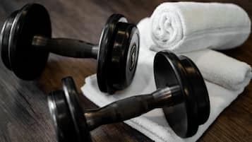 Two black dumbbells and a white towel on a wooden surface.