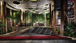 A grand staircase leading to a seating area with a red carpet, surrounded by lush greenery and wooden pillars. - Sun Island Hotel & Spa Legian (Kuta)