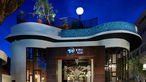 A modern building with a prominent 'Topix Asia' sign, outdoor seating, and a staircase leading to the entrance. - Sun Island Hotel & Spa Legian (Kuta)
