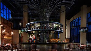 A bar area with a central circular bar, multiple stools, and a decorative ceiling structure. - Sun Island Hotel & Spa Legian (Kuta)