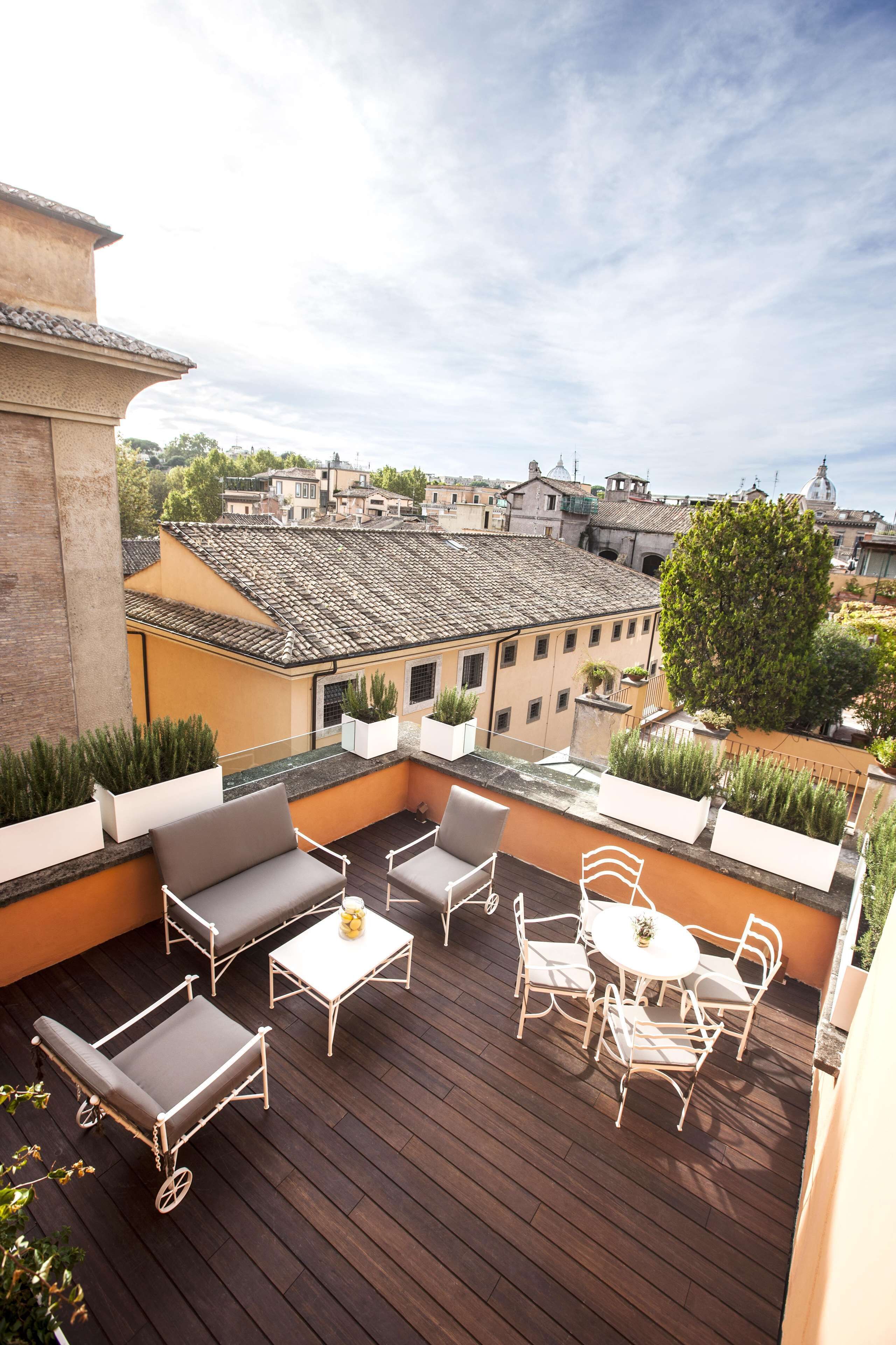 Terraza en la azotea con mobiliario exterior, plantas en macetas y vistas a la ciudad.