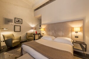 Una camera d'albergo con un letto grande, due comodini, una sedia e una scrivania.
