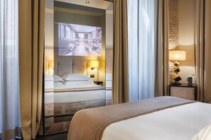 A hotel room with a bed, a television screen, and a nightstand with a lamp.