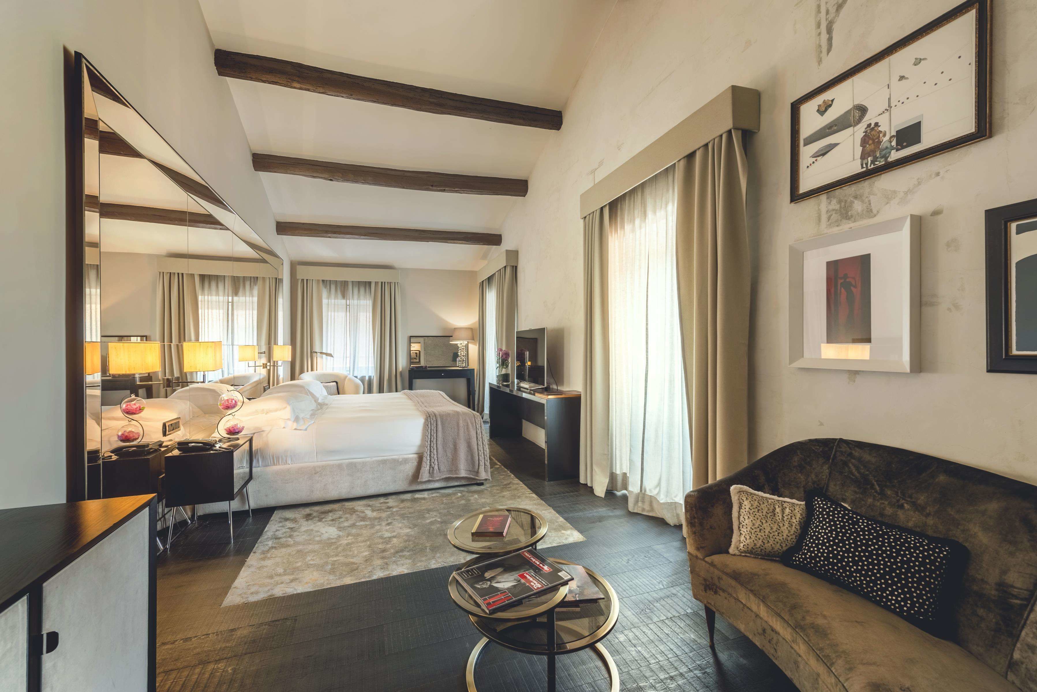 Une chambre d’hôtel équipée d’un lit, d’un bureau, d’une télévision, d’un canapé et d’un grand miroir.