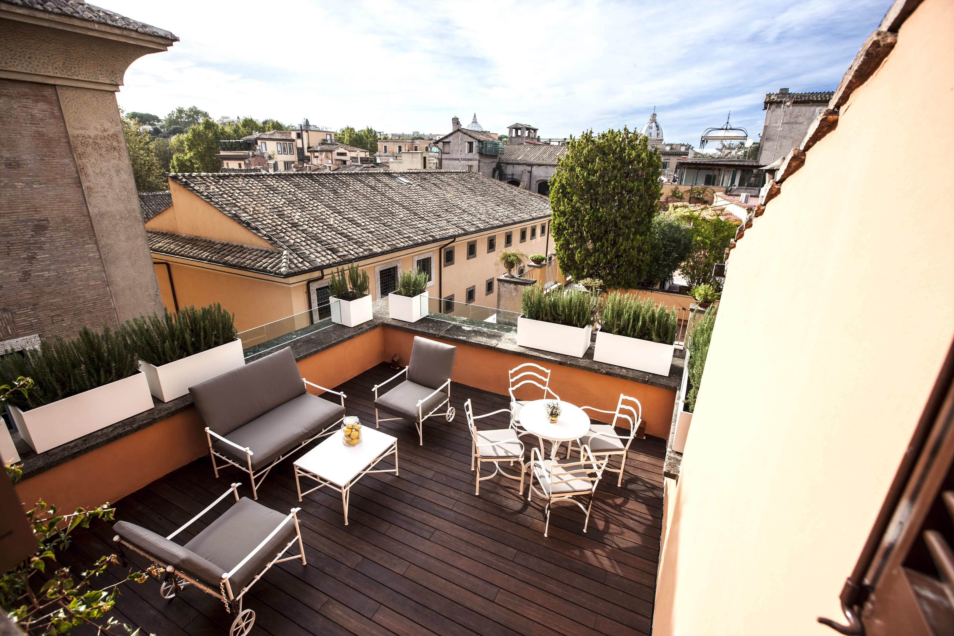 En takterrass med utemöbler, utsikt över stadsbilden och en byggnad med ett tak täckt av tegelpannor.