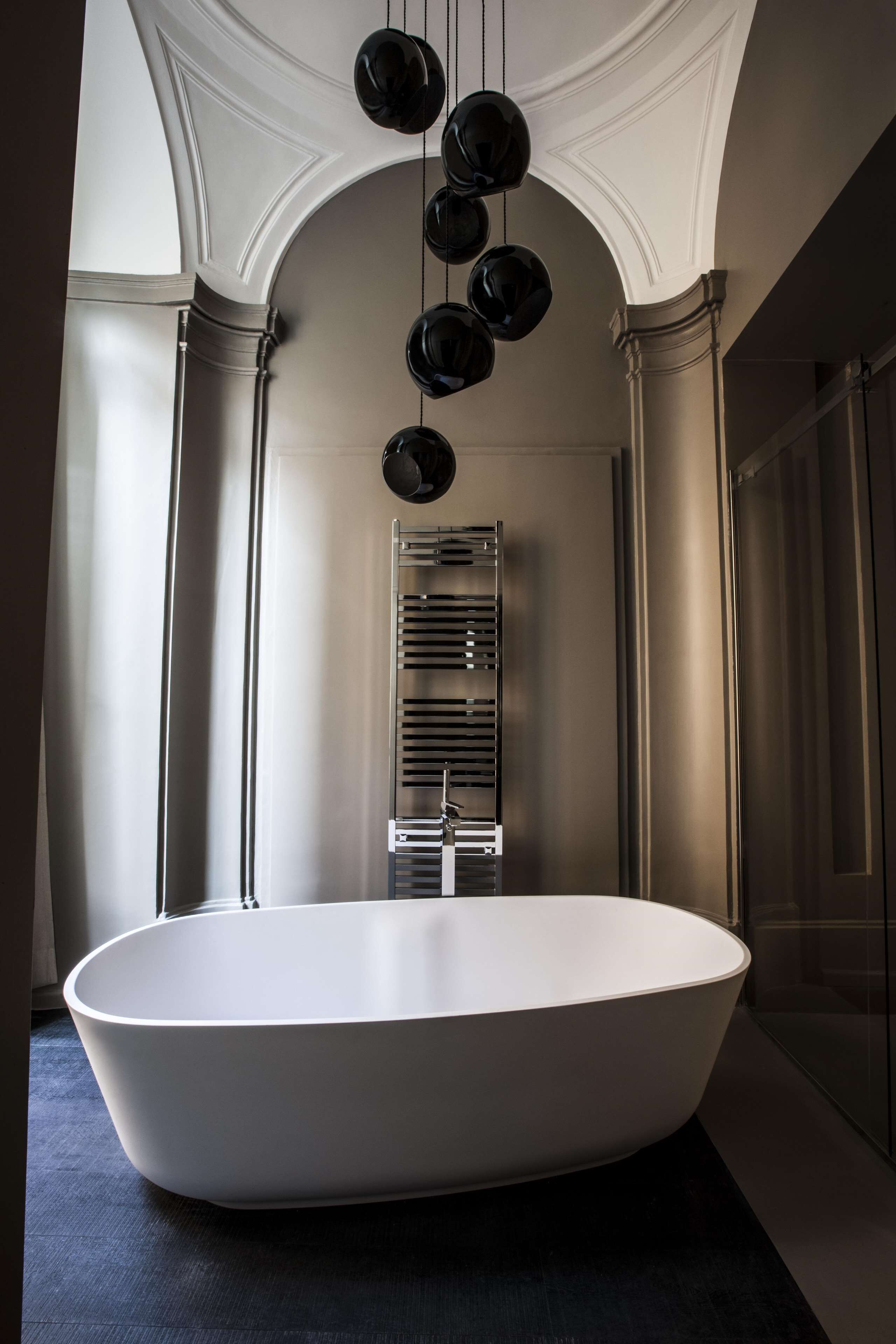 A modern bathroom with a freestanding bathtub, a wall-mounted towel rack, and a ceiling light fixture.
