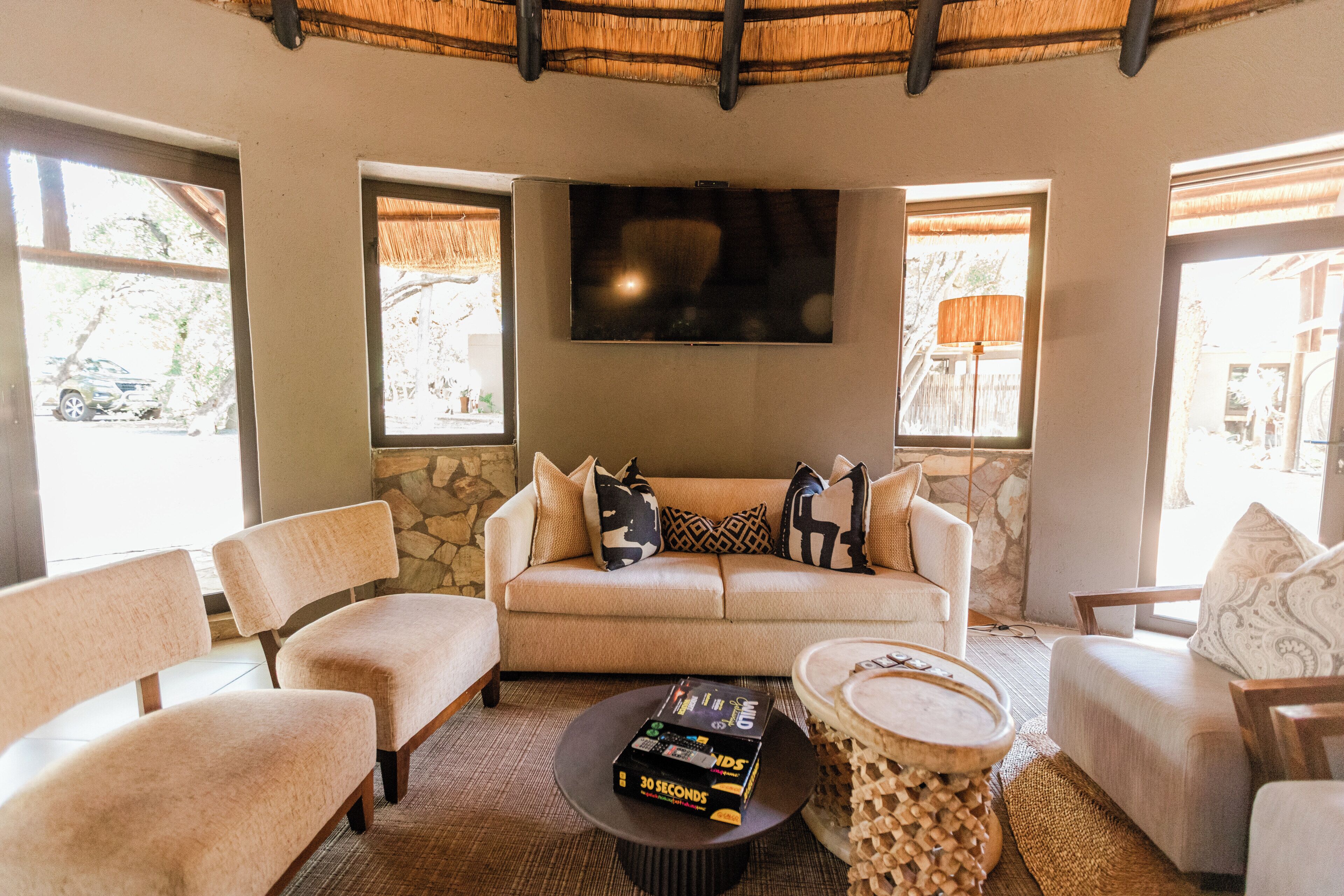 A living room with a sofa, two armchairs, a coffee table, a TV, and a stone wall.