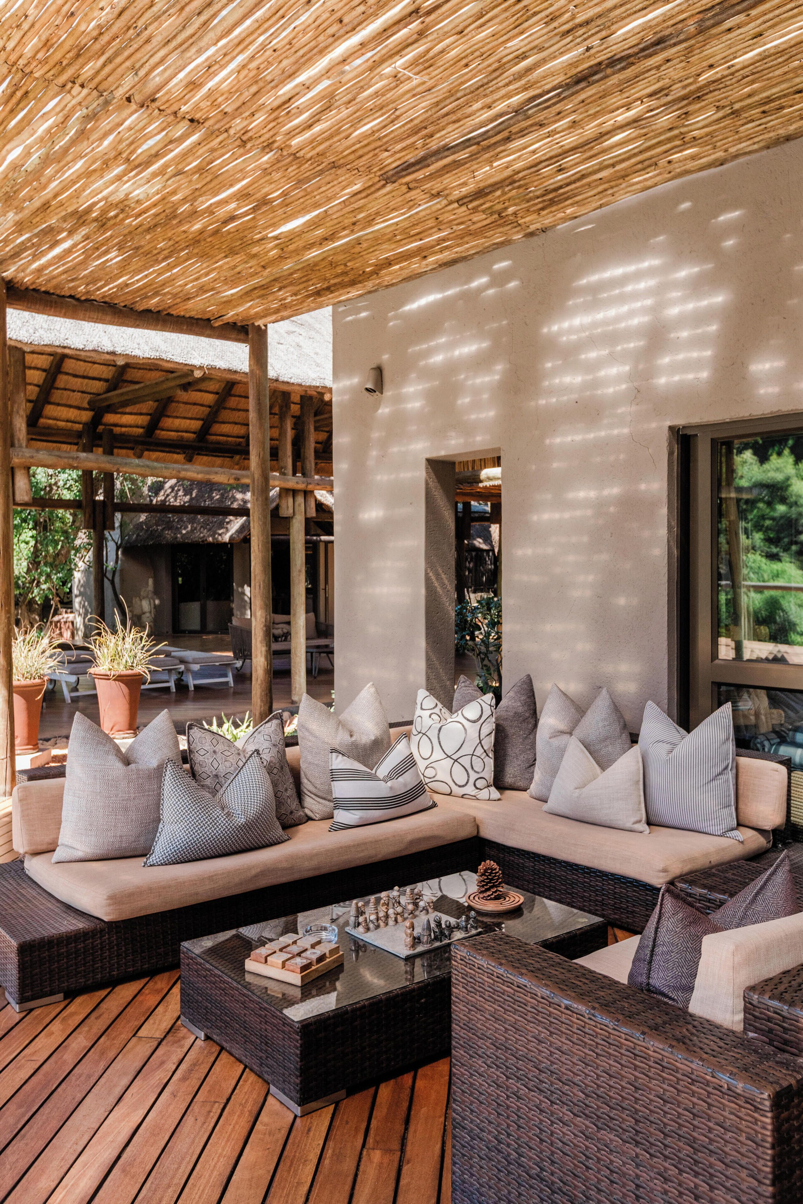 A covered outdoor seating area with a sofa, cushions, and a coffee table.