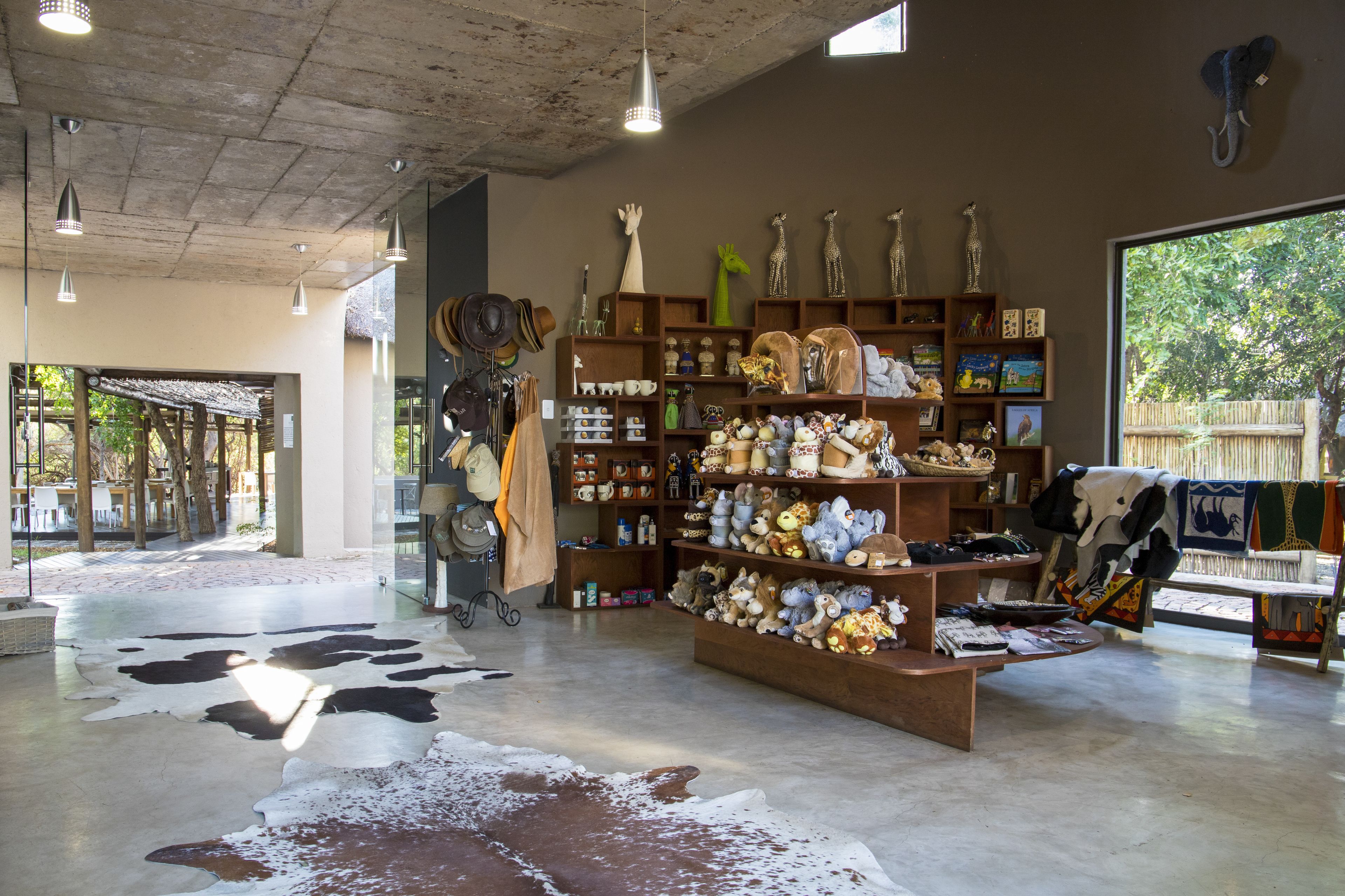 A store interior with shelves of various items, a central display of stuffed animals, and a cowhide rug on the floor.