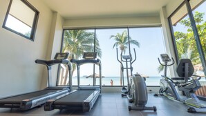 Academia com esteiras, elípticos e vista para a praia.