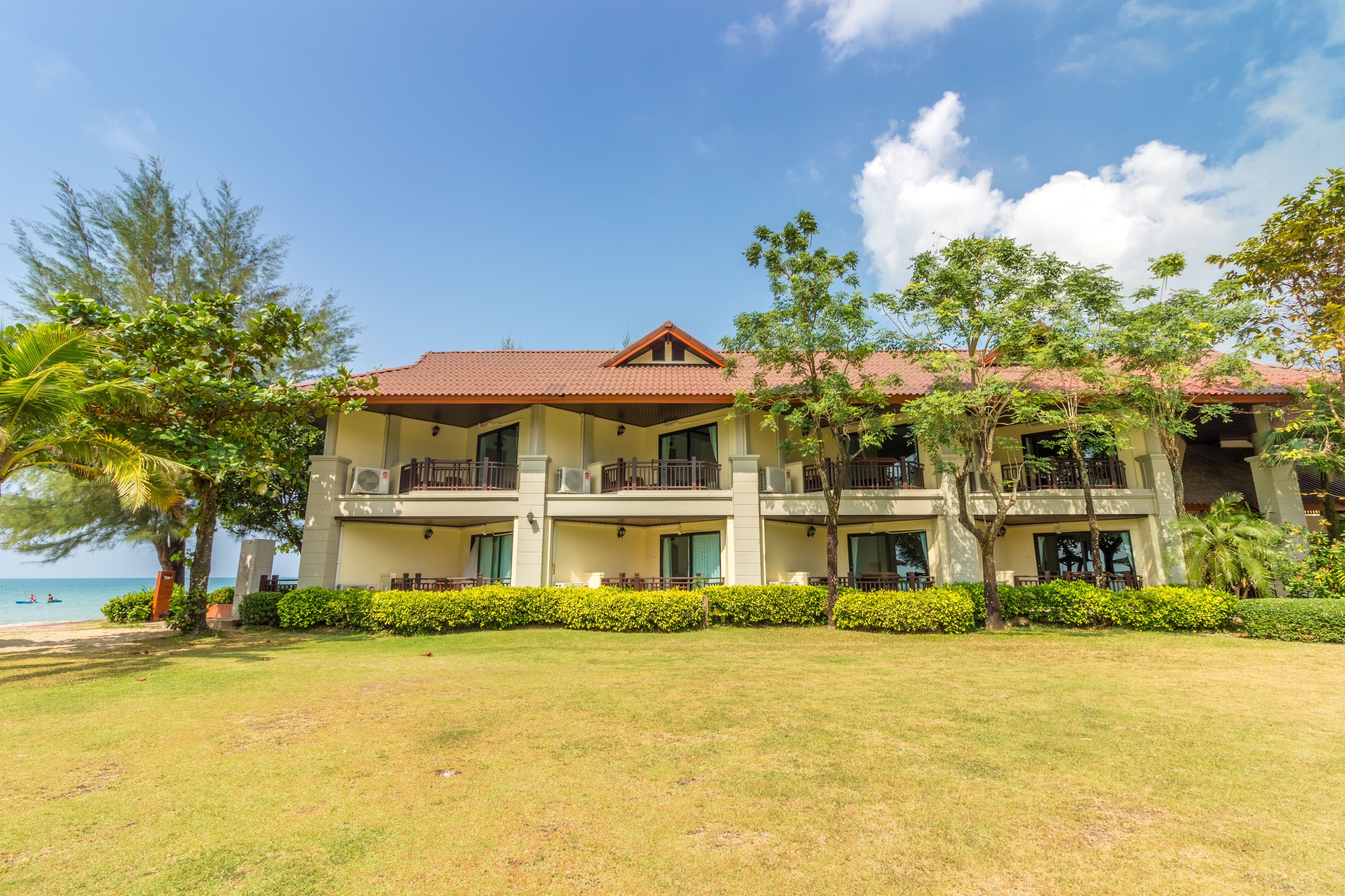 A multi-story hotel with a red-tiled roof, balconies, and a well-maintained lawn.