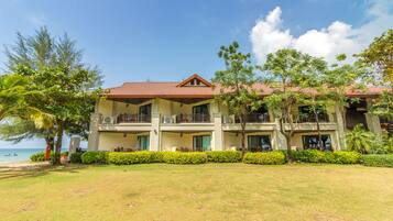 A multi-story hotel with a red-tiled roof, balconies, and a well-maintained lawn.