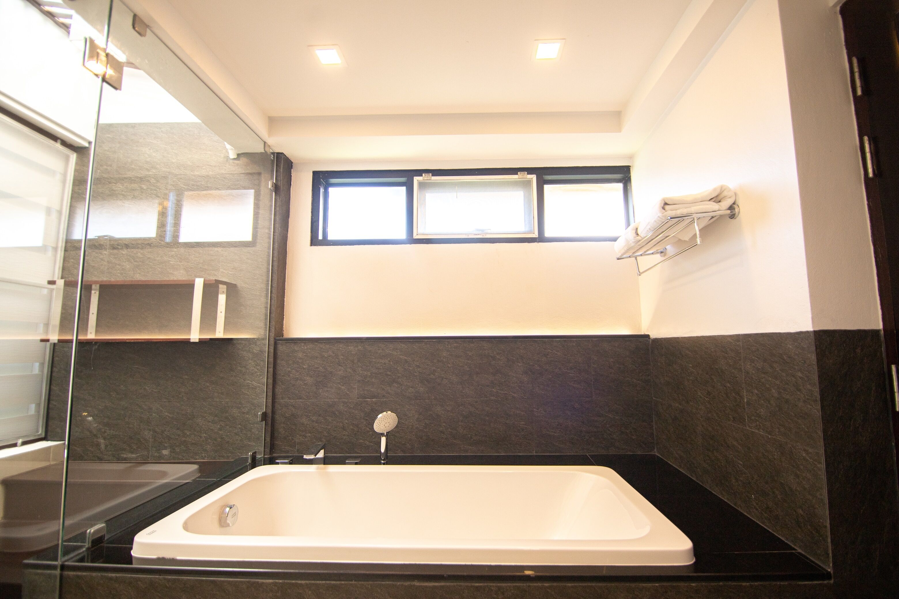 A modern bathroom with a bathtub, a glass shower enclosure, and a window providing natural light.
