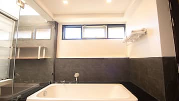 A modern bathroom with a bathtub, a glass shower enclosure, and a window providing natural light.