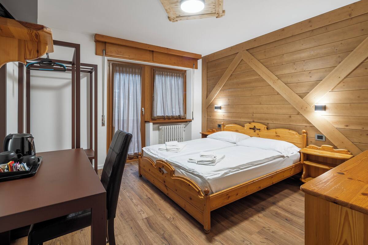 A wooden-framed room with a bed, a desk, and a chair.