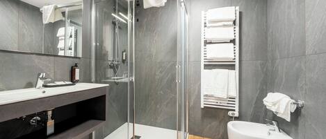 A modern bathroom with a glass shower enclosure, a white sink, and a toilet.